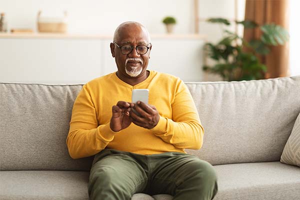 Man sitting on a couch while using his mobile phone