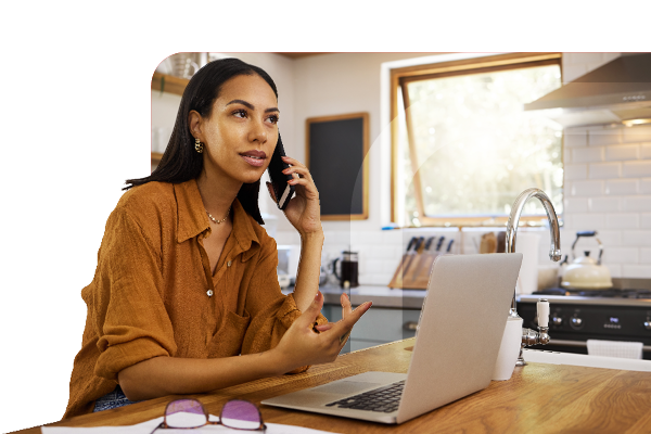 Woman seated next to a laptop using a mobile phone